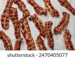 Slices of tasty fried bacon on white table, top view