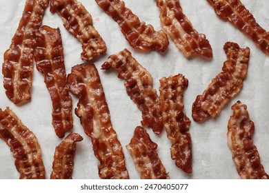 Slices of tasty fried bacon on white table, top view