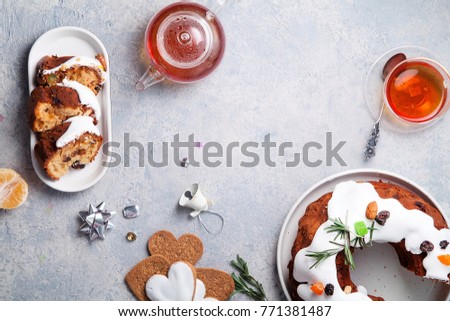 Slices of traditional christmas cake with dried fruits soaked in rum and sugar glaze. Teatime with heart-shaped ginger cookies. Christmas background with festive decoration. Copy space.