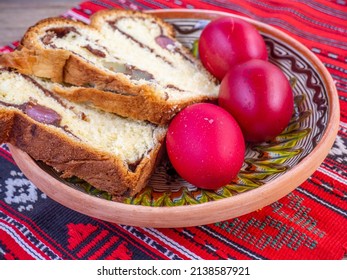 Scheiben aus traditionellem Osterbrot oder Cozonac- und traditionell dekorierten Eiern, romanisches Ostergericht, auf Tischdecken