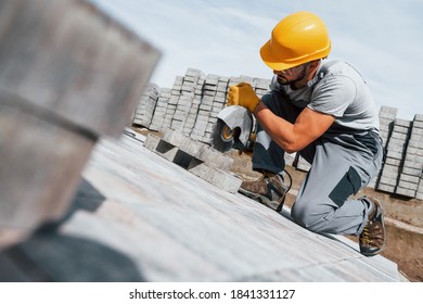 Slicing by circular saw. Male worker in yellow colored uniform have job with pavement. - Powered by Shutterstock