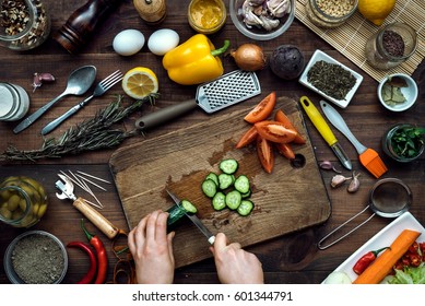 Slicing By Hand Cucumber On Wooden Kitchen Table With Vegetables Cooking Ingredients