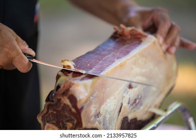 Slicing Dry-cured Ham Prosciutto. Professional Cutter Carving Slices From A Whole Bone, Cutting First Layer Of Smoked Ham.
