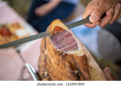 Slicing Dry-cured Ham Prosciutto. Professional Cutter Carving Slices From A Whole Bone, Cutting First Layer Of Smoked Ham.