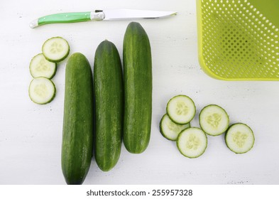 Slicing Green Cucumbers For Salad Food Preparation On Rustic White Wood Table, Overhead.