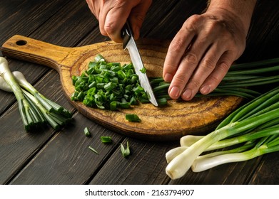 Slicing green onions on a cutting board with a knife for cooking vegetarian food. Peasant dish. - Shutterstock ID 2163794907