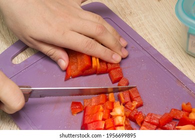 Slicing red pepper on the board. Hands cut the bell pepper into cubes. Cooking in the home kitchen. - Powered by Shutterstock