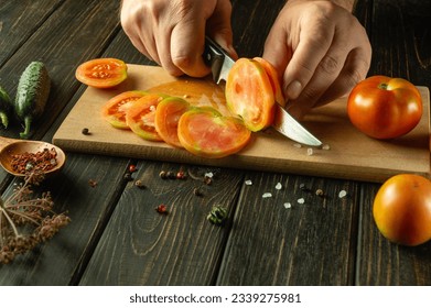 Slicing tomatoes for cooking vegetarian food. Knife in the chef hand for cutting a tomato. Vegetable diet idea. - Powered by Shutterstock