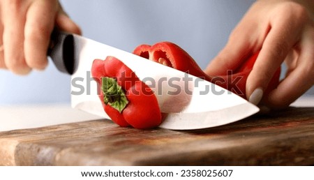 Slicing vegetables. Female hands cut sweet Red Bell Pepper on a cutting board. Cooking in the kitchen. Food preparation. Close-up.