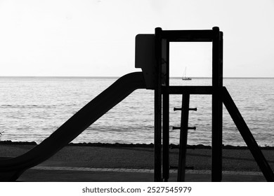 Slide on the beach with framed sailboat in the horizon - Powered by Shutterstock