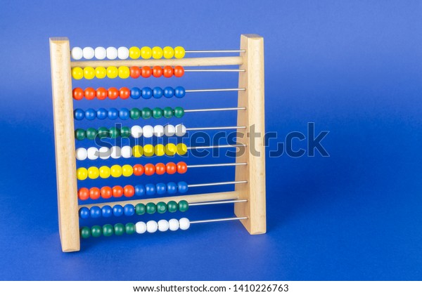 A slide rule with colorful balls, blue background\
and copy space