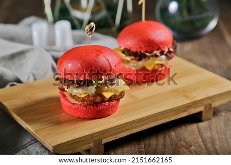 Slider chicken burger with cheese and pickles close up red color butter bread