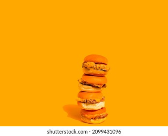 Sliders With Cheese (mini Hamburgers). Four Sliders In Tower With Solid Yellow Background. Plain Hamburger Bun