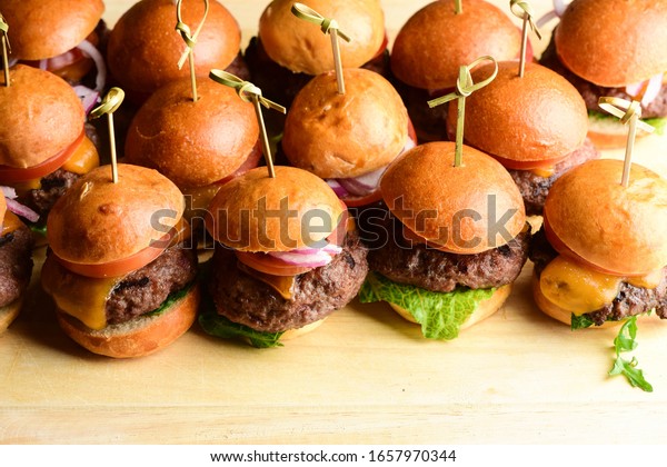 Sliders. Mini\
grass fed cheddar cheese burgers topped with lettuce, tomatoes,\
onions, pickles, mayo and mustard served on toasted buns. Classic\
American restaurant bar\
appetizer.