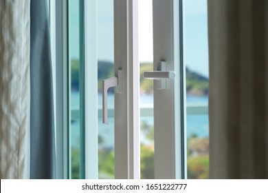 Sliding door of a balcony. Close-up of the lock on the door with and nice landscape of background. White PVC door and security glass.