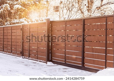 Sliding Entrance Gate in Winter. Wide Automatic Metal Modern Gate with Remote Control Installed. Modern Fence with Horizontal sections of Fence.