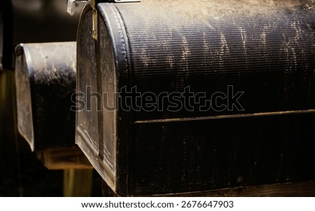 slightly angled view of several mailboxes supported on wooden posts. close up of weathered black letterboxes background with copy space