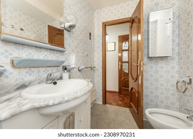 A slightly dated full bathroom with a square mirror, vintage tiles with blue accents and a gray marble countertop