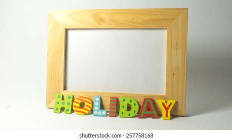 Slightly Defocused And Close-up Colourful And Cute Wooden Alphabet That Forms The Word Holiday On Empty Photo Frame. Concept Of Types Of Day And Day In A Week. Copy Space,