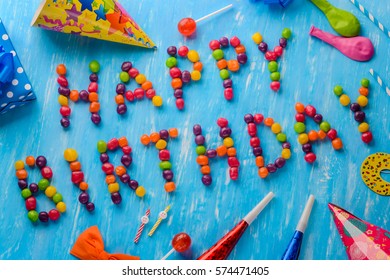 Slightly diagonally birthday card composition. Jelly beans, lollipops, party hats and noisemakers on a blue background. To brighten someone's day. - Powered by Shutterstock