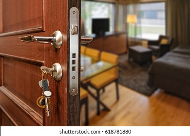Slightly opened wooden door with group of modern keys on keychain as a concept for home ownership or for security and door policy privacy