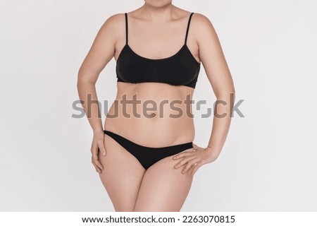 A slightly overweight female figure in black sports underwear without a face close-up. Self acceptance and body positivity. unrecognizable