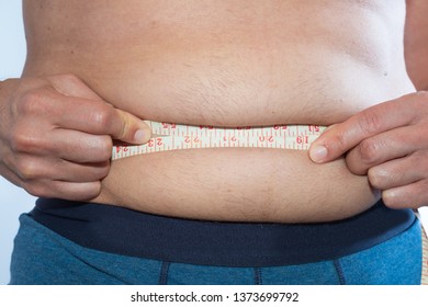 A Slightly Overweight Man Measures His Waist