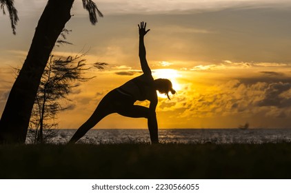 Slihouette woman doing exercise at beach during sunset 
