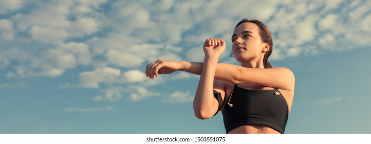 Slim Athletic Girl Performs Stretching Exercises On The Roof Of An Unfinished Building, Urban Background. Enjoys Silence And Freedom. Panoramic Image Banner, Toned.