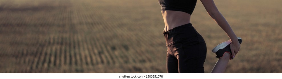 Slim Athletic Girl Performs Stretching Exercises On The Roof Of An Unfinished Building, Urban Background. Enjoys Silence And Freedom. Panoramic Image Banner, Toned.