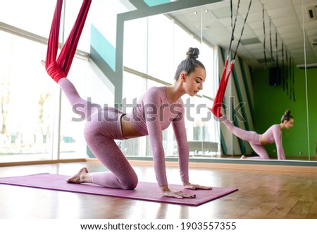 Slim athletic woman in hammock performs stretching and aerial yoga exercises. Sport motivation and healthy lifestyle