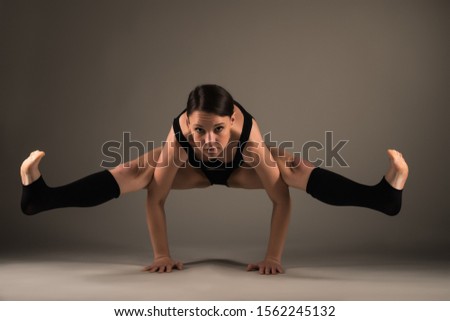 Slim athletic young woman doing a handstand asana yoga studio on a dark background. Flexible and healthy athletic body concept. Advertising space