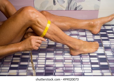 Slim Attractive Young Man Using Measuring Tape To Measure Weight Loss And Muscle On Leg.