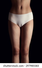 Slim body of a sexy young Asian woman standing in beautiful white panties over black background