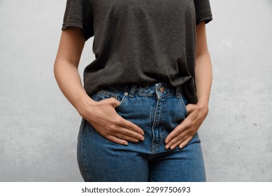 Slim figure of a girl. Girl wearing in a casual balnk gray t-shirt and jeans. Weight loss progress, figure demonstration.