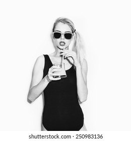 Slim funky blonde woman in black body drink cocktail with orange juice. Emotion. Toned. White background, not isolated