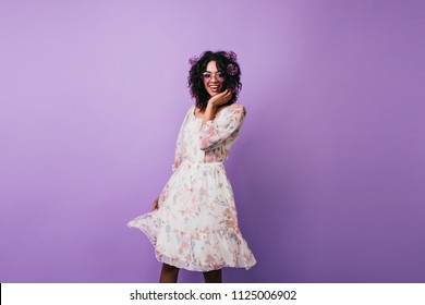 Slim girl with alliums in hair happy dancing on purple background. Pleasant african young woman in vintage dress posing in studio. - Powered by Shutterstock