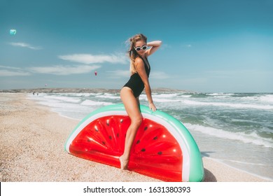 Slim girl in fashion style swimwear playing with inflatable watermelon mattress at sand beach and enjoying tropical paradise by sea. Perfect summer vacation, good vibes.