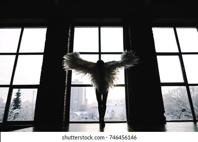 Slim girl in lingerie with wings Standing against the window