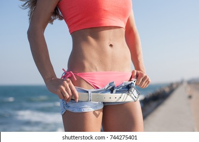 Slim Girl Standing Arms Akimbo. Part Of Torso Of Attractive Young Woman With Sagging Pants And Hands On Hips