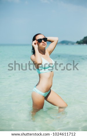 slim girl in swimsuit and sunglasses at tropical sea resort 