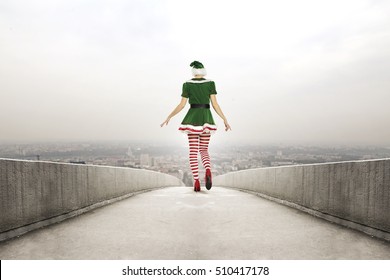 Slim green woman elf on bridge in city and winter time 