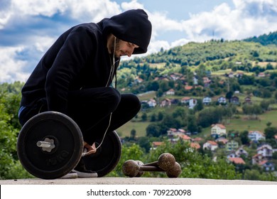Slim guy lifting weights outside 