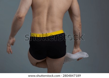 A slim guy is warming up before a grueling workout to avoid injury. Body parts: a man's back with problematic skin, the effects of using steroids and supplements to build muscle mass
