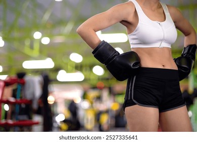 slim healthy beautiful female boxer body wearing boxing gloves. female athlete with boxing gloves doing akimbo pose on gym ring. confident boxer training for health and muscle for body pose akimbo. - Powered by Shutterstock