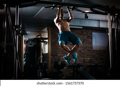 Slim muscular man doing pullups shirtless in the gym, high contrast image - Powered by Shutterstock