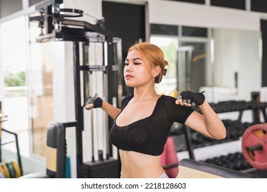 A Slim And Sexy Asian Woman In A Black Crop Top Does Dynamic Chest Stretch Before A Workout Session At The Gym.