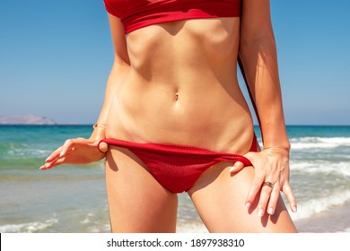 Slim sexy girl with a perfect figure in a red bikini on the beach. Fashion summer concept.