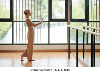 Slim Smiling Young Woman In Comfy Aparrel Taking Selfie In Dance Studio Mirror