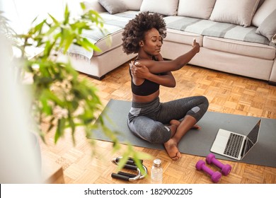 Slim Sportswoman In Sportswear Warming-up Muscles Before Workout Doing Stretching Exercise Sitting On Floor At Home. The Time To Start Getting Fit Is Right Now. Fit Woman Stretching At Home